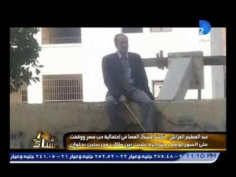 مدير مدرسة يجلس على السور ممسكًا بـعصا