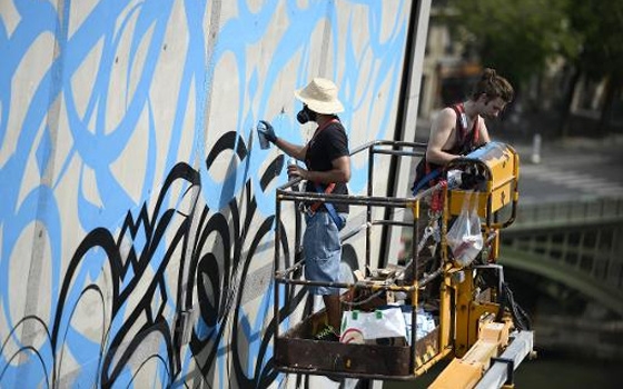   مصر اليوم - فنان شاب يرسم لوحة جدارية على واجهة معهد العالم العربي